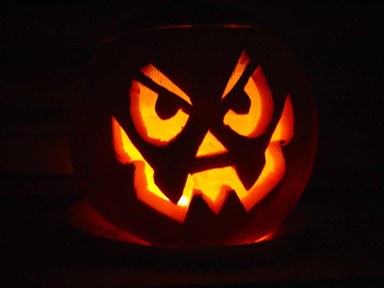 photo of an illuminated Jack O'Lantern with a michievious face carved on it